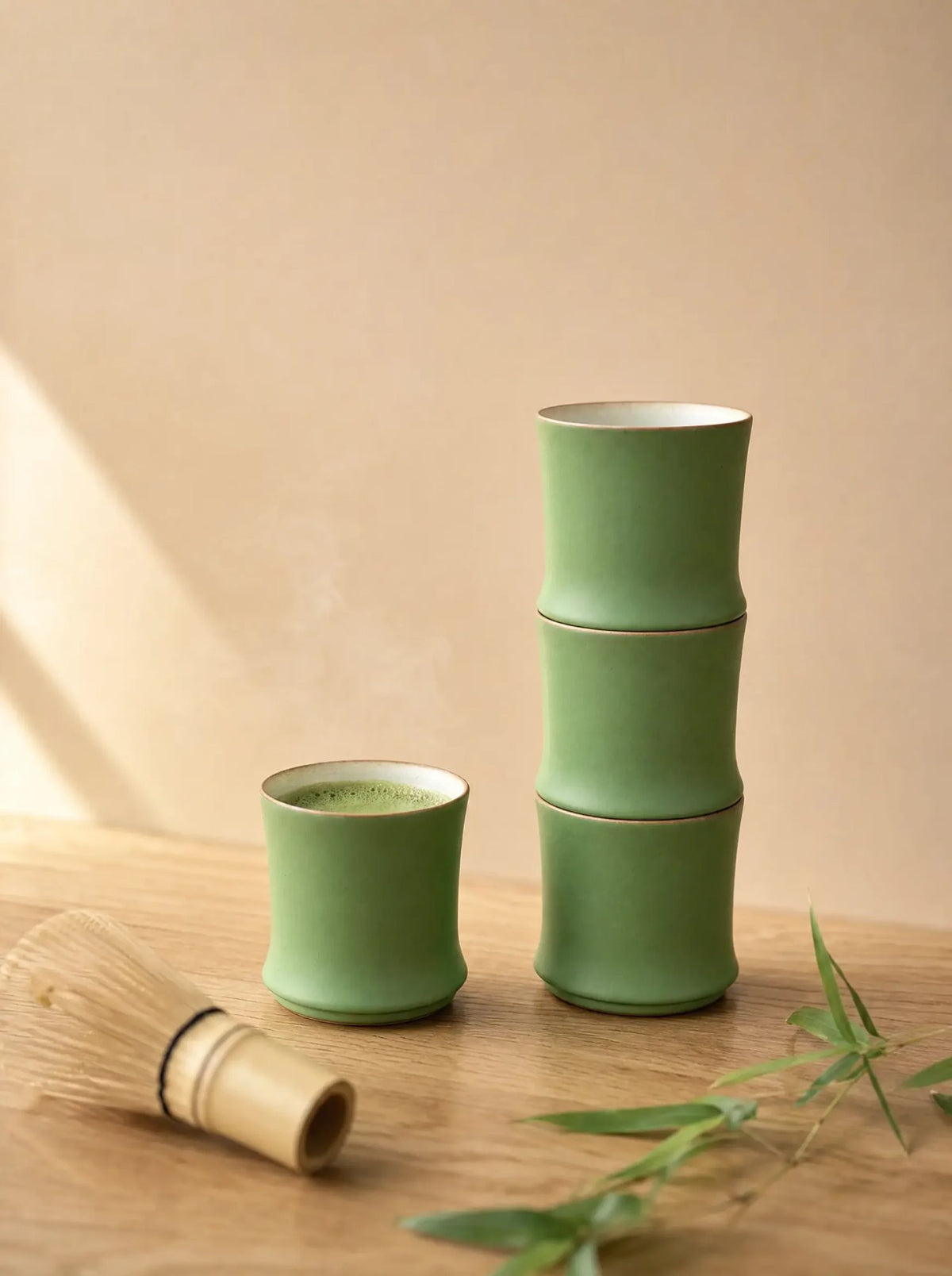 Stackable bamboo ceramic cups stacked beside a cup of matcha